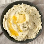 A bowl of mashed potatoes with melted butter on top.