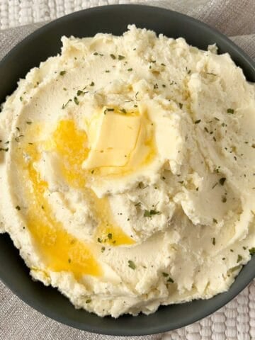 A bowl of mashed potatoes with melted butter on top.