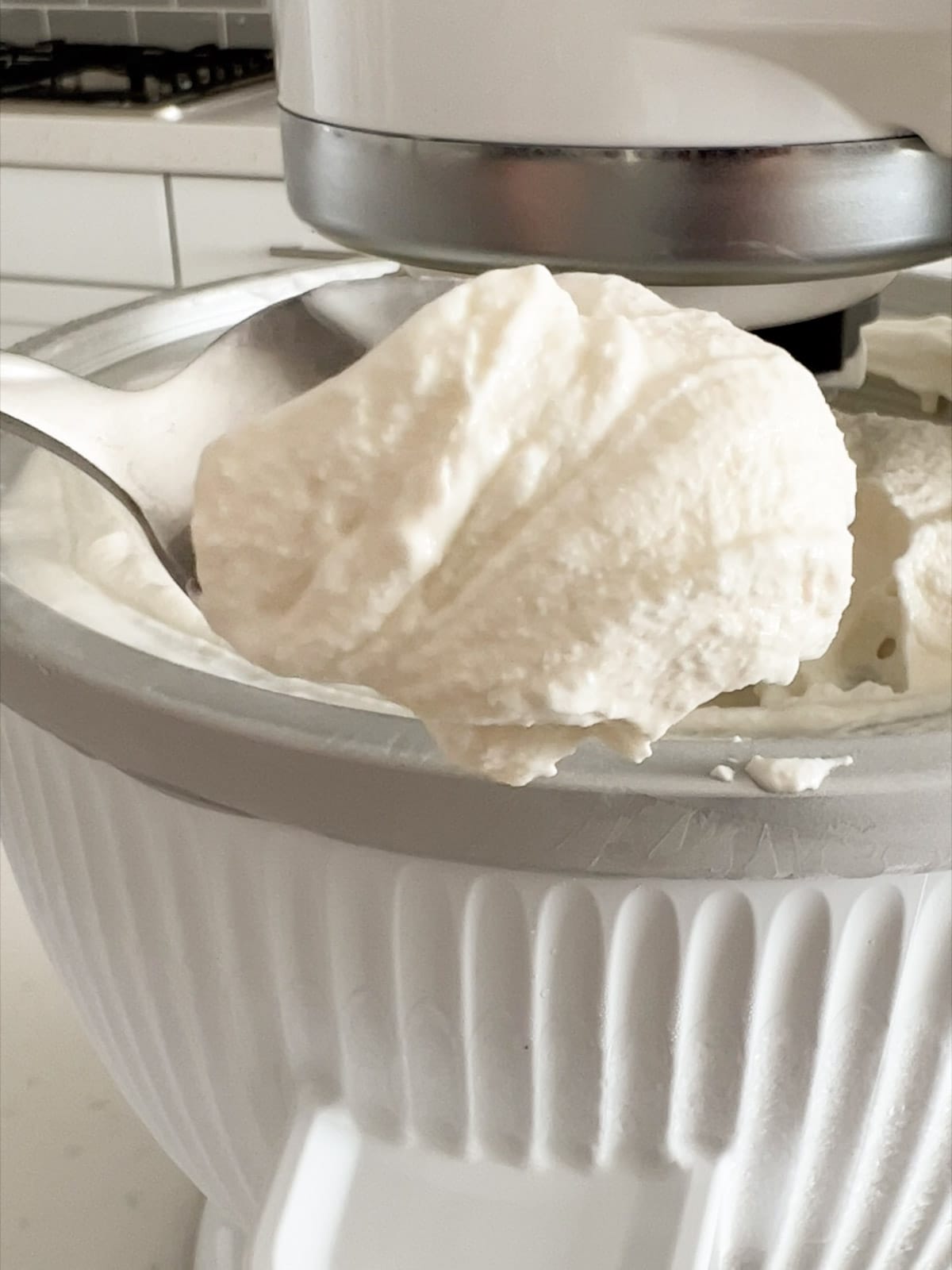 A spoon with vanilla ice cream the consistency of soft serve.