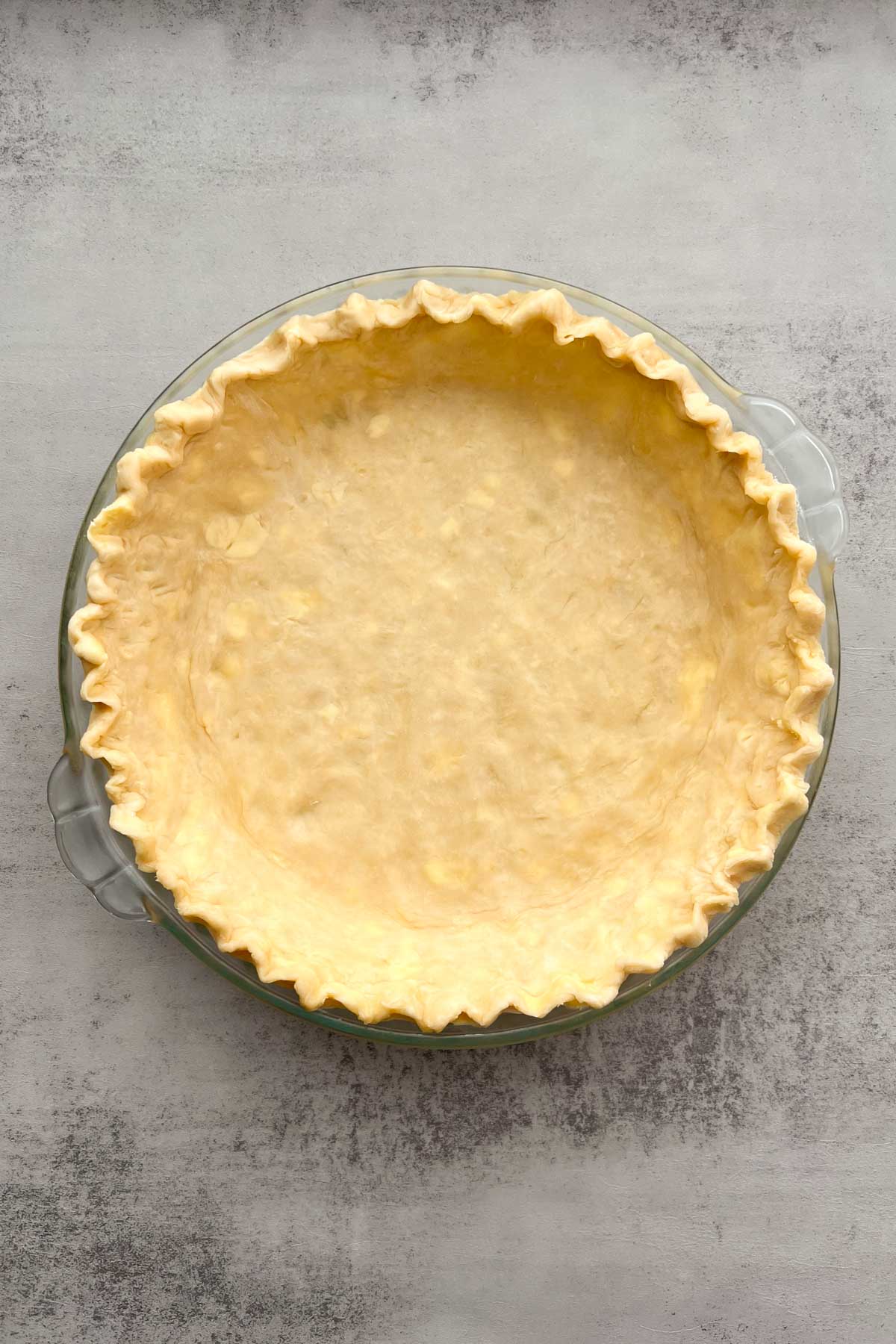 Pie crust with fluted edges in a pie dish.