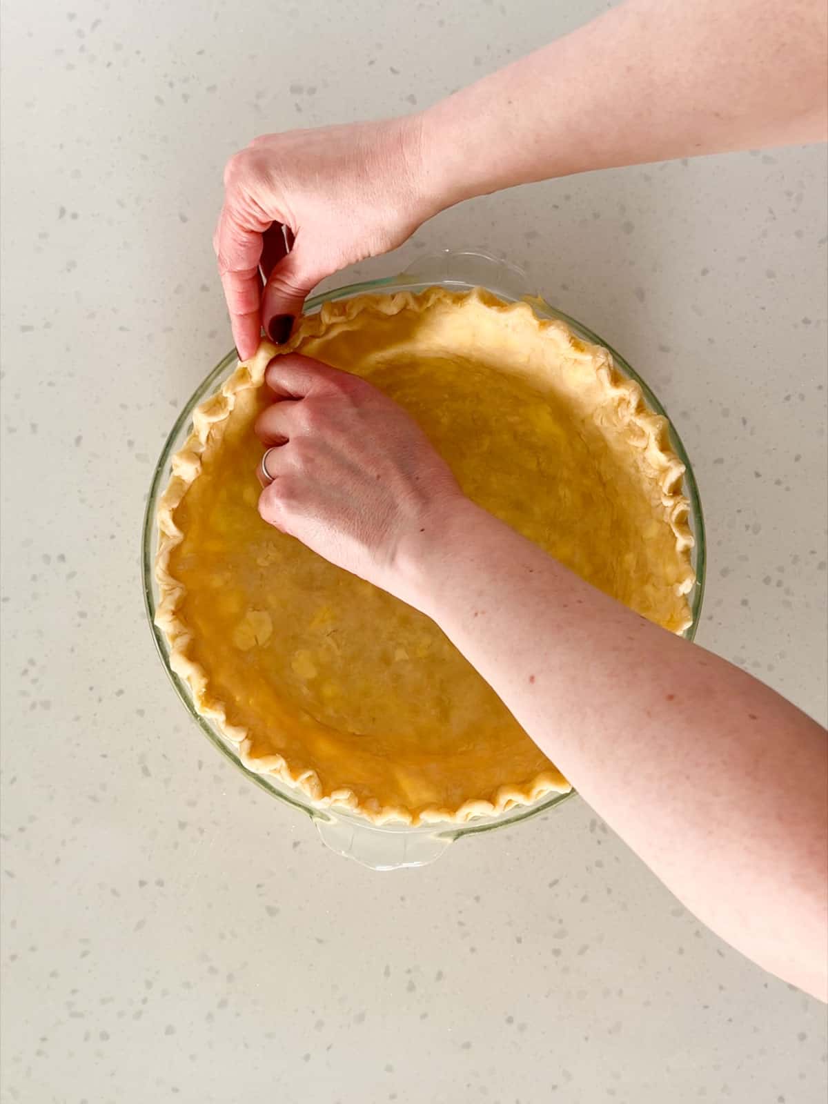 The edges of a pie crust are fluted by pinching the dough around the knuckle of the forefinger.