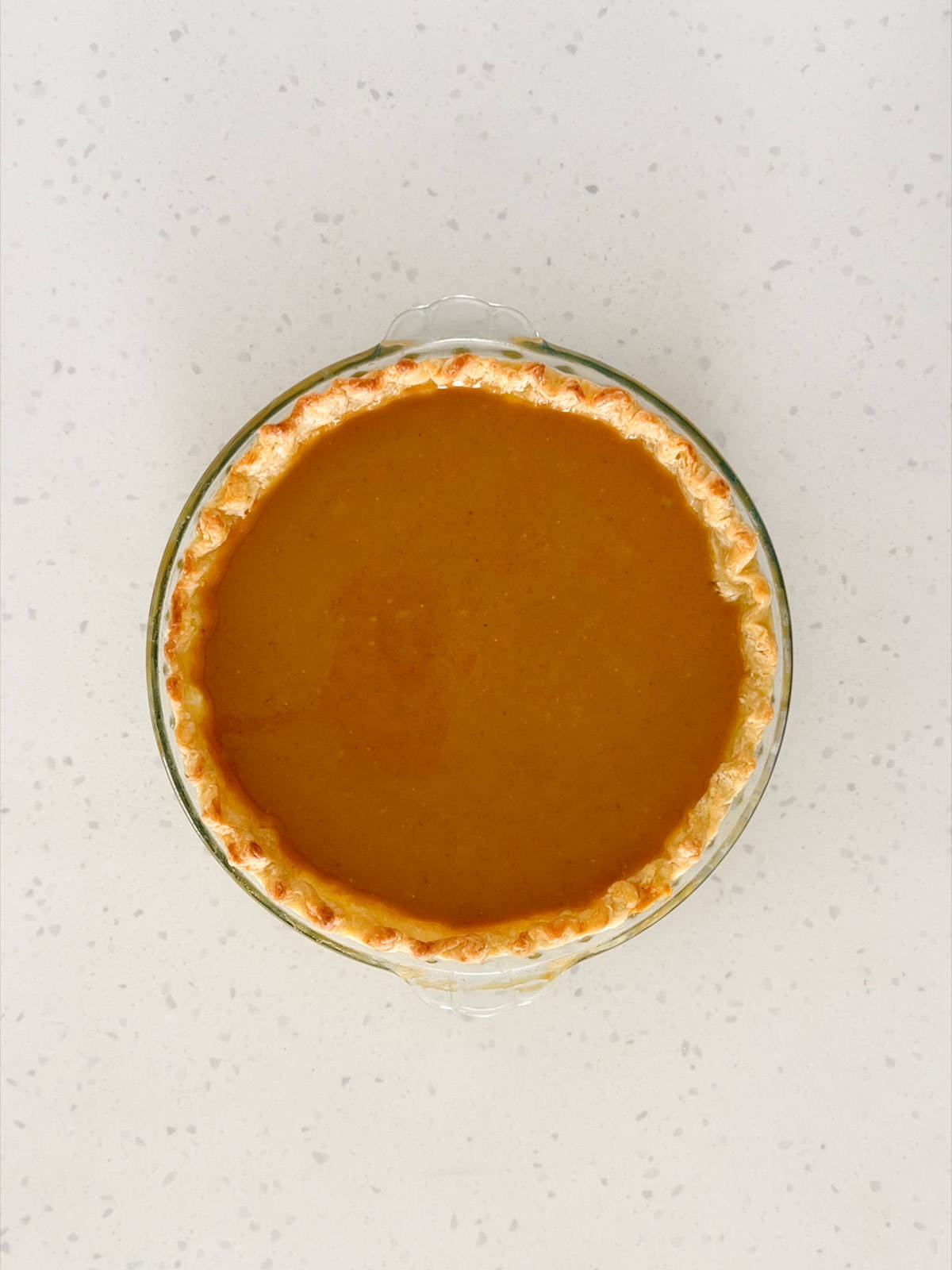 Pumpkin pie filling is poured into the par-baked pie crust.