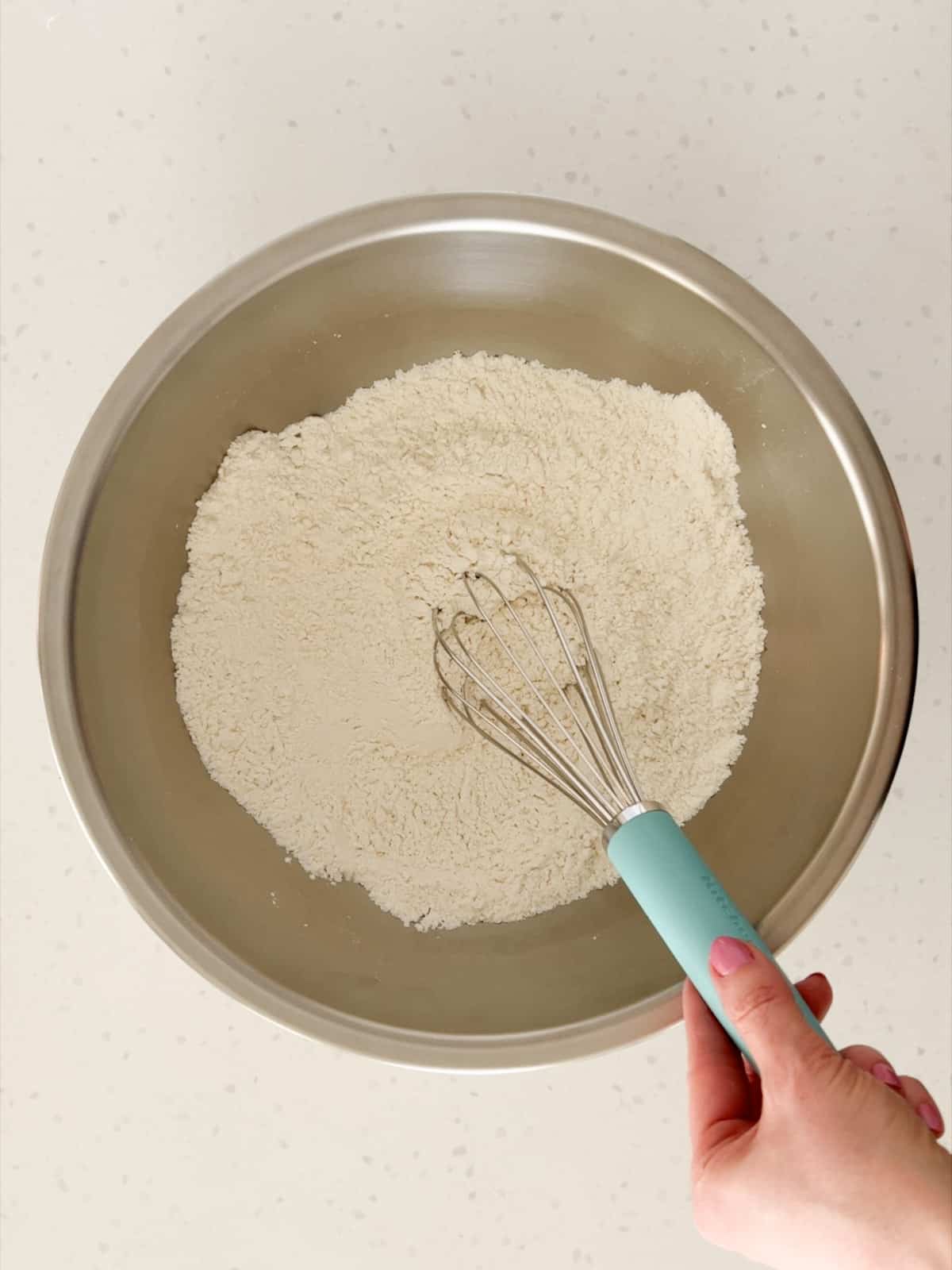 Flour, baking powder, and salt are whisked together in a bowl.