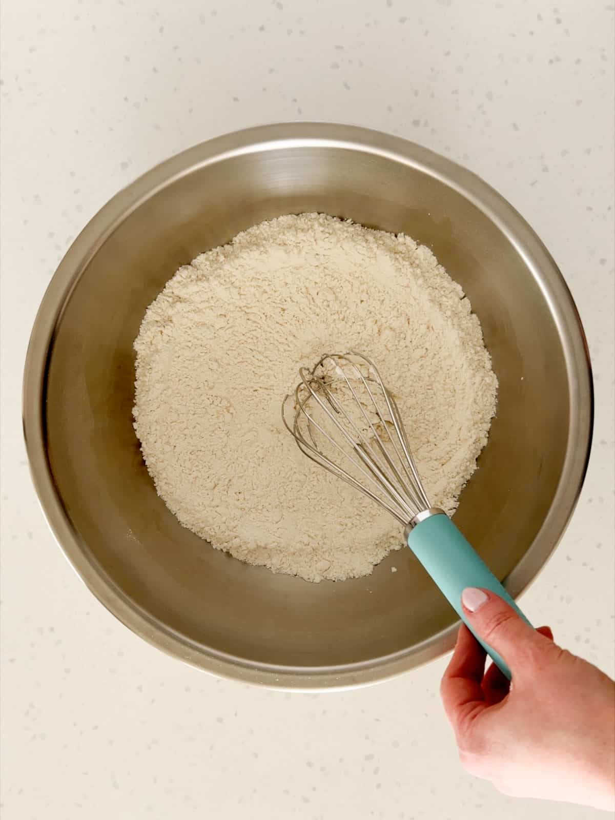 Flour and salt are whisked together in a large bowl.