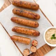 Air fryer chicken sausage served on a wooden tray with a mustard dip.