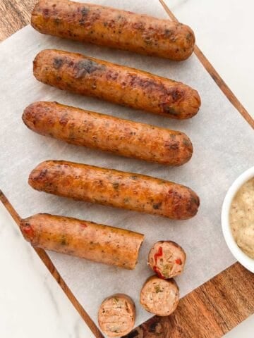 Air fryer chicken sausage served on a wooden tray with a mustard dip.