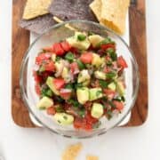 A bowl of avocado pico de gallo served with tortilla chips.