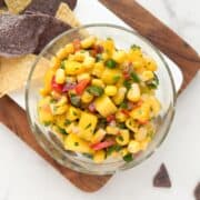 A bowl of mango corn salsa with tortilla chips.