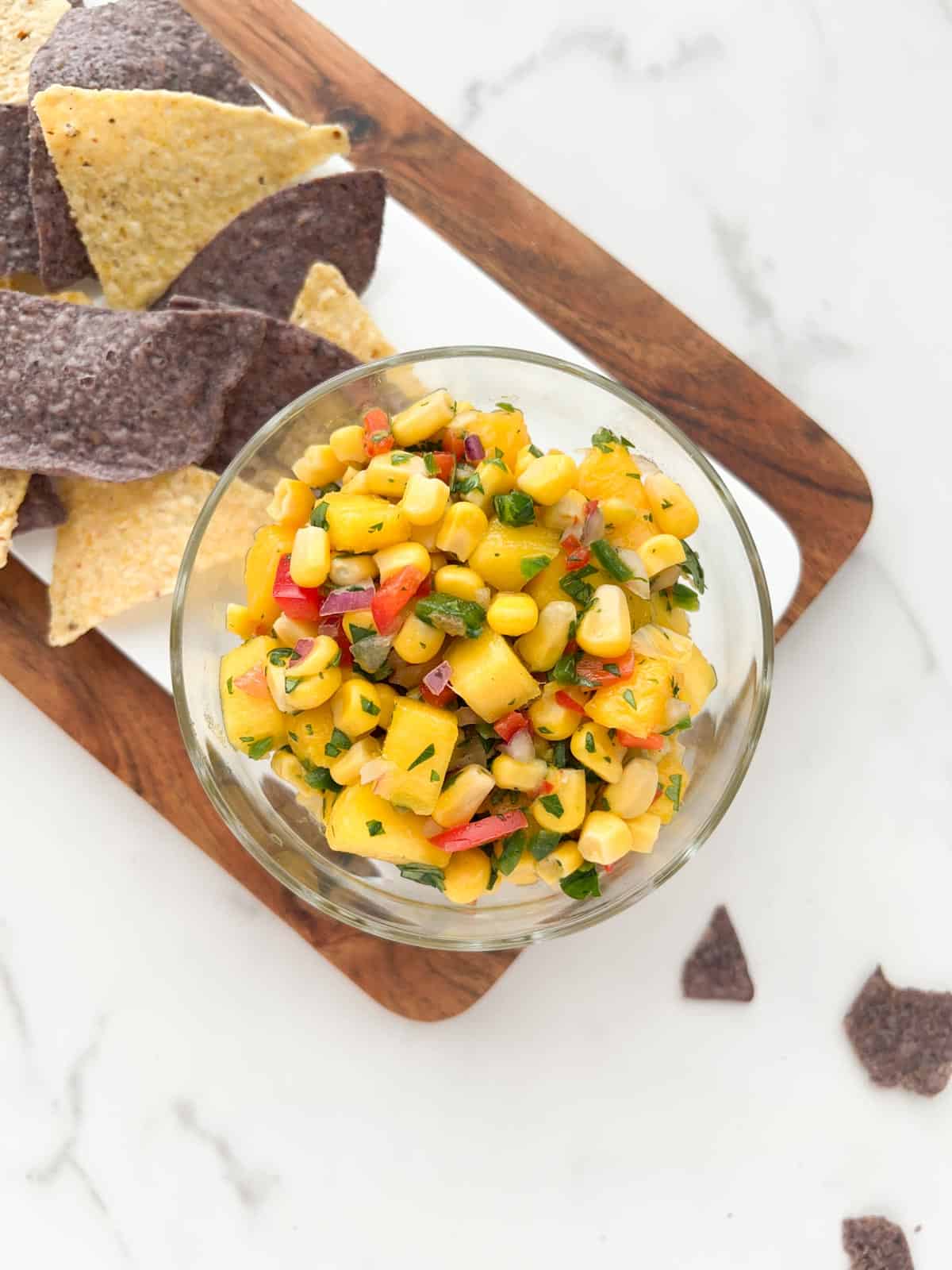 Mango corn salsa in a bowl with tortilla chips to the side.