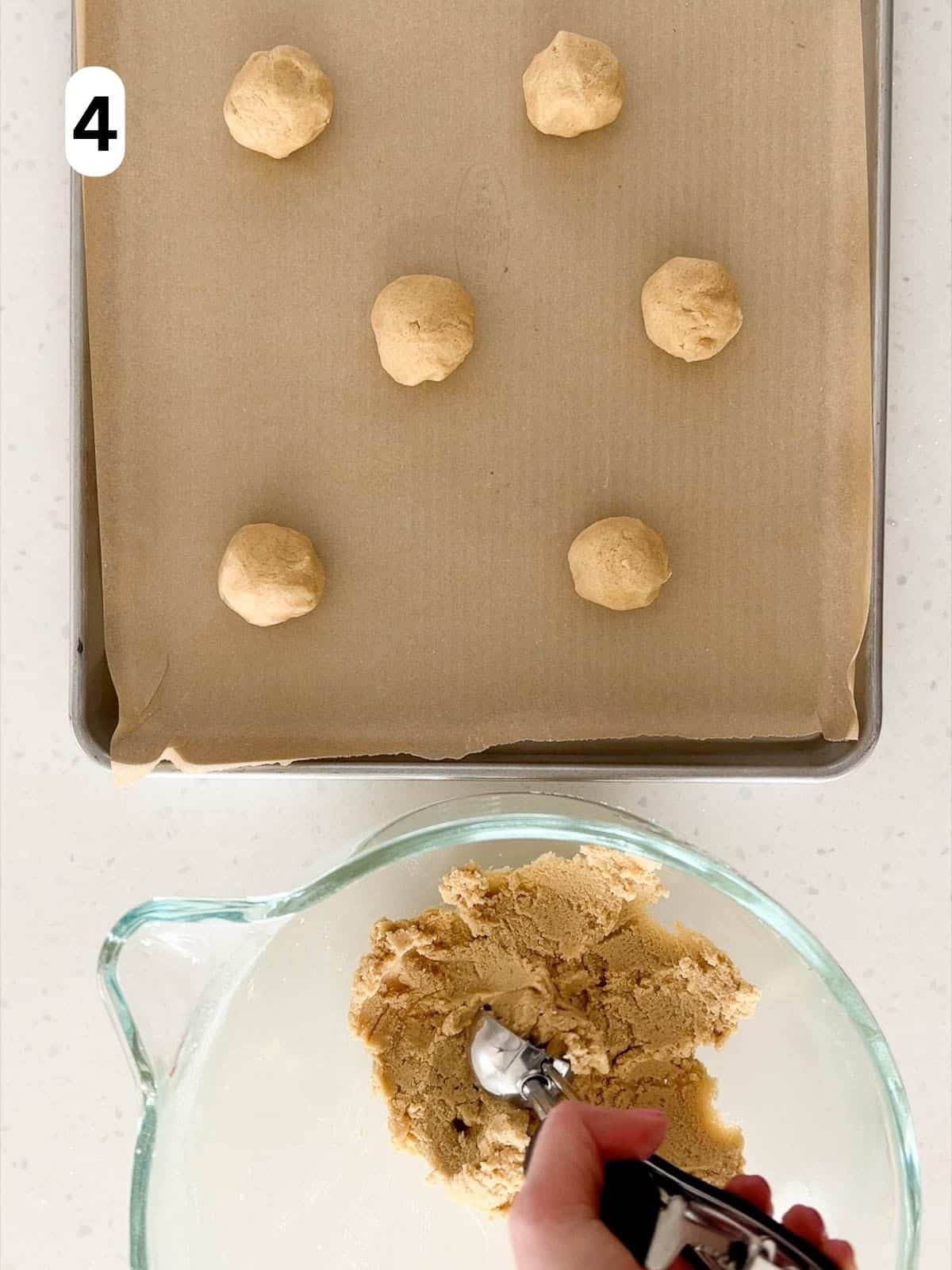 Balls of cookie dough are scooped onto a prepared baking sheet.
