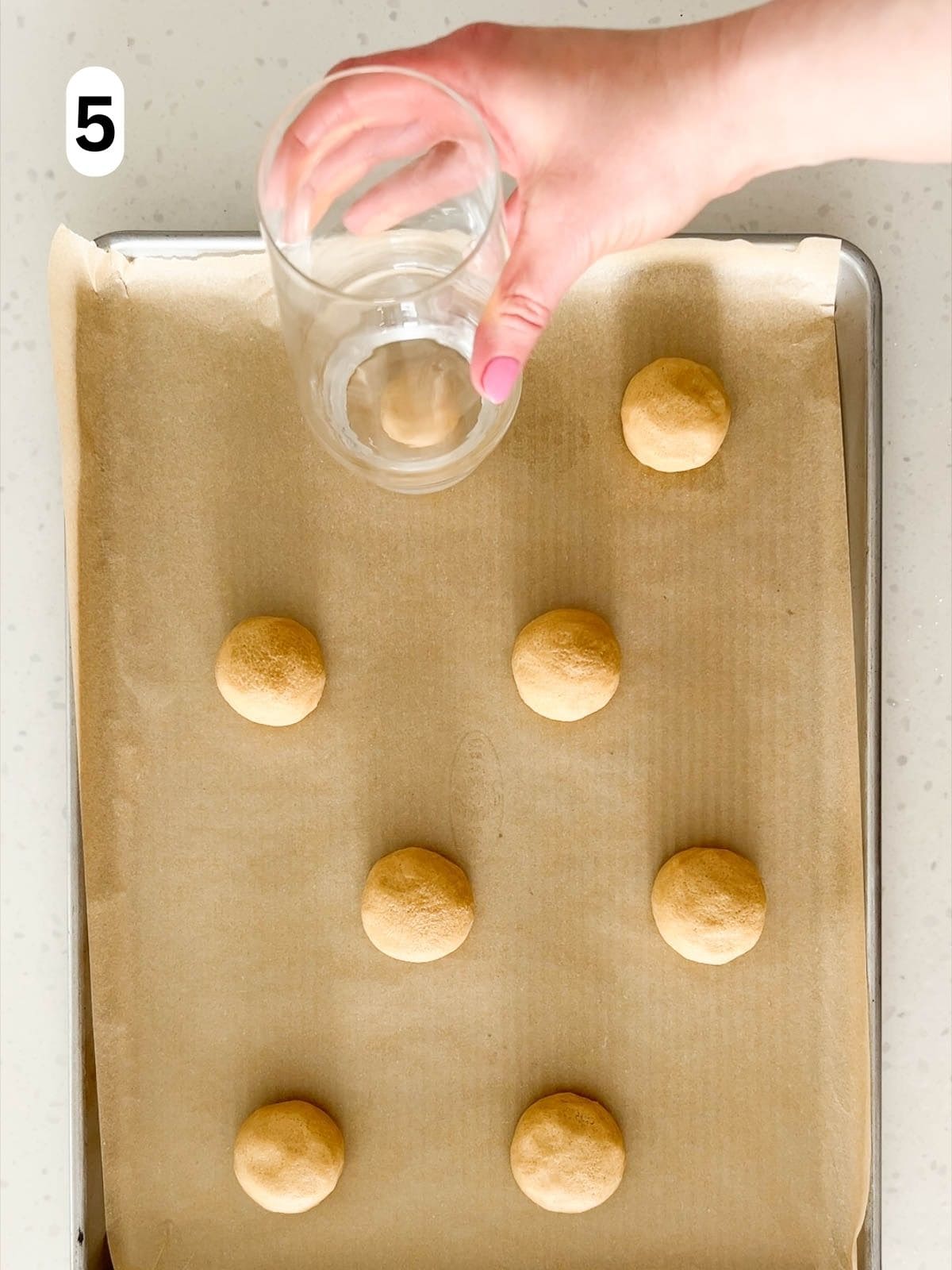 The balls of dough are flattened into discs with the bottom of glass.