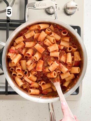 The rigatoni pasta is tossed in the sauce until evenly coated.
