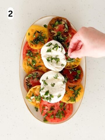 Chopped basil is sprinkled on top of the tomatoes and burrata.