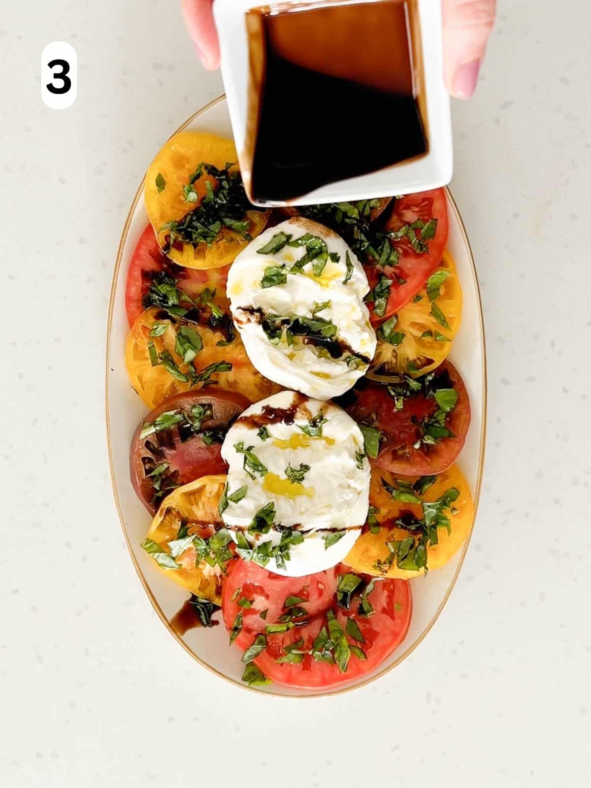 Balsamic vinegar is drizzled on top of the tomatoes and burrata.
