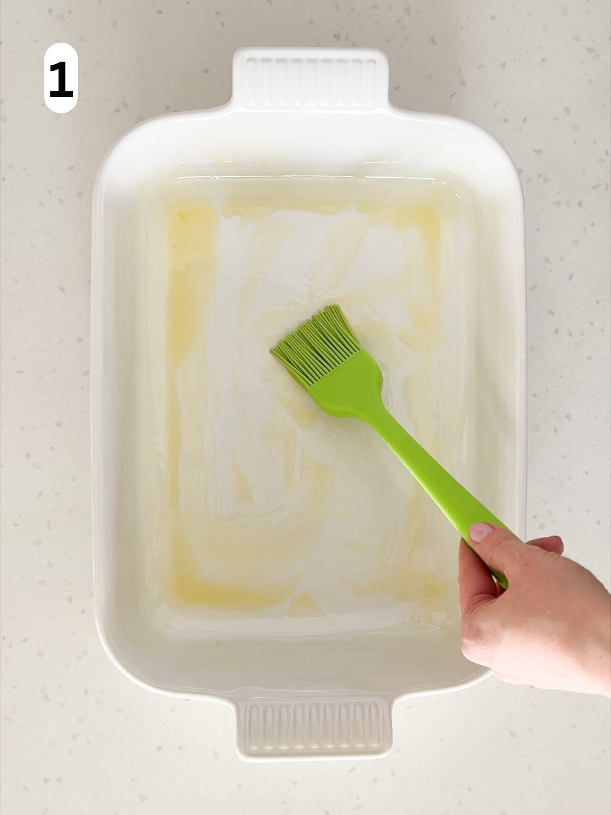 A baking dish is brushed with olive oil.