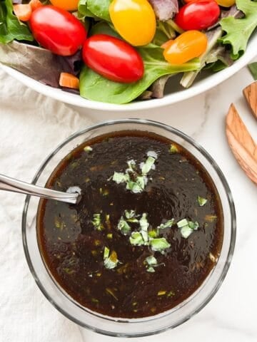 Basil balsamic vinaigrette in a bowl with salad to the side.