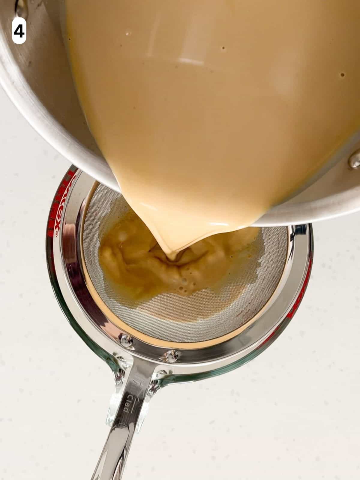 The panna cotta is poured through a fine mesh strainer.