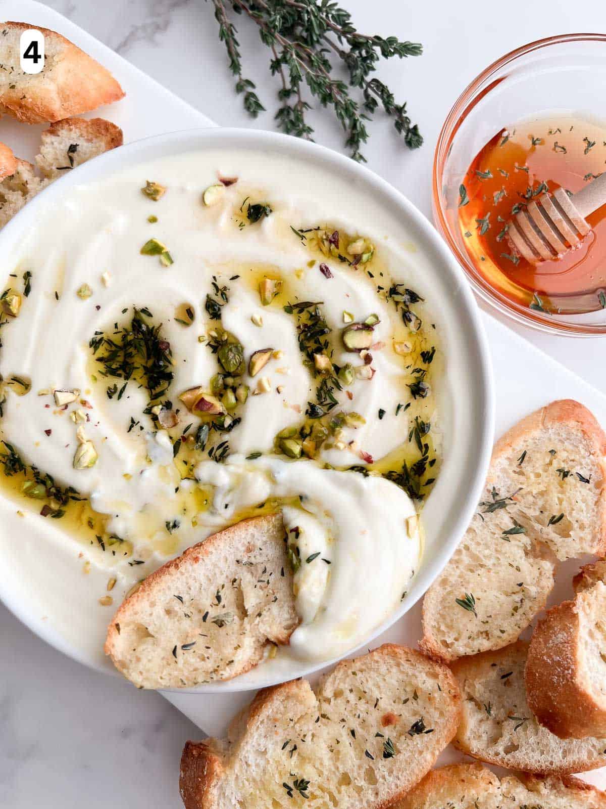 The whipped ricotta dip is garnished with the honey olive oil topping and chopped pistachios.