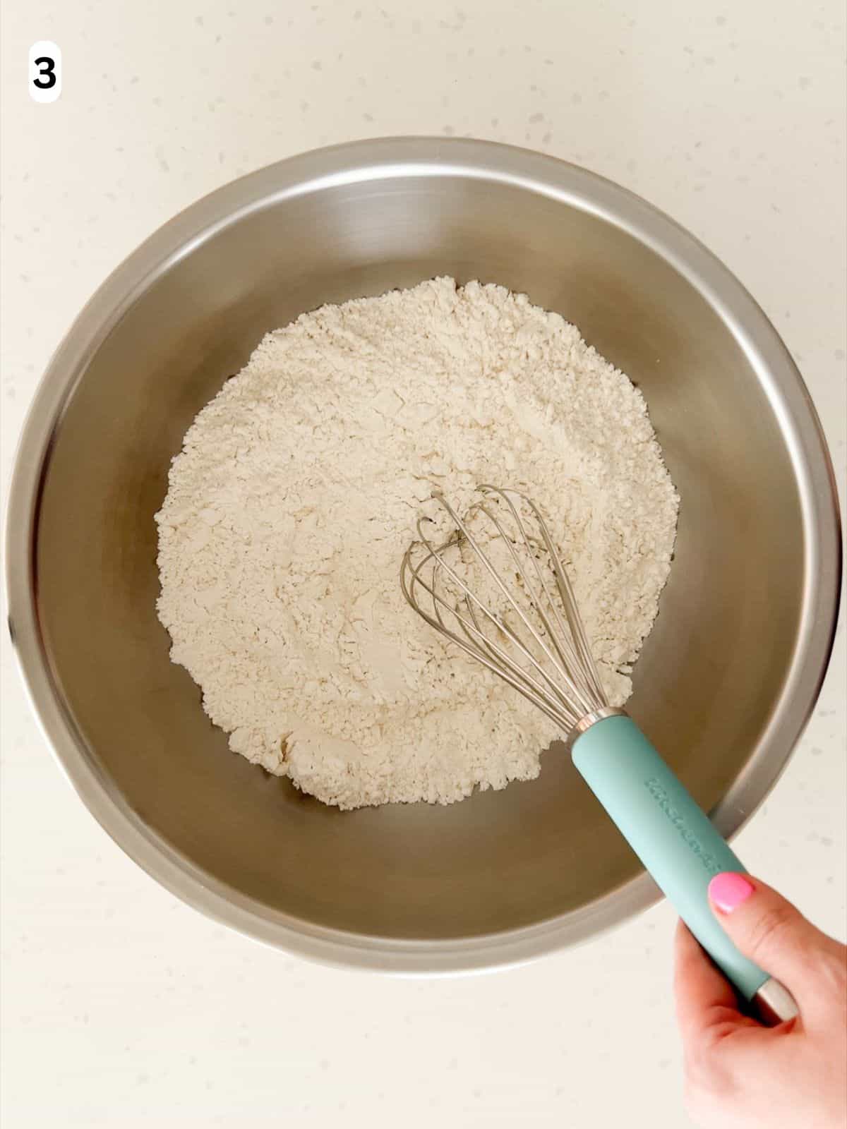 Flour, baking powder, and salt are whisked in a bowl.