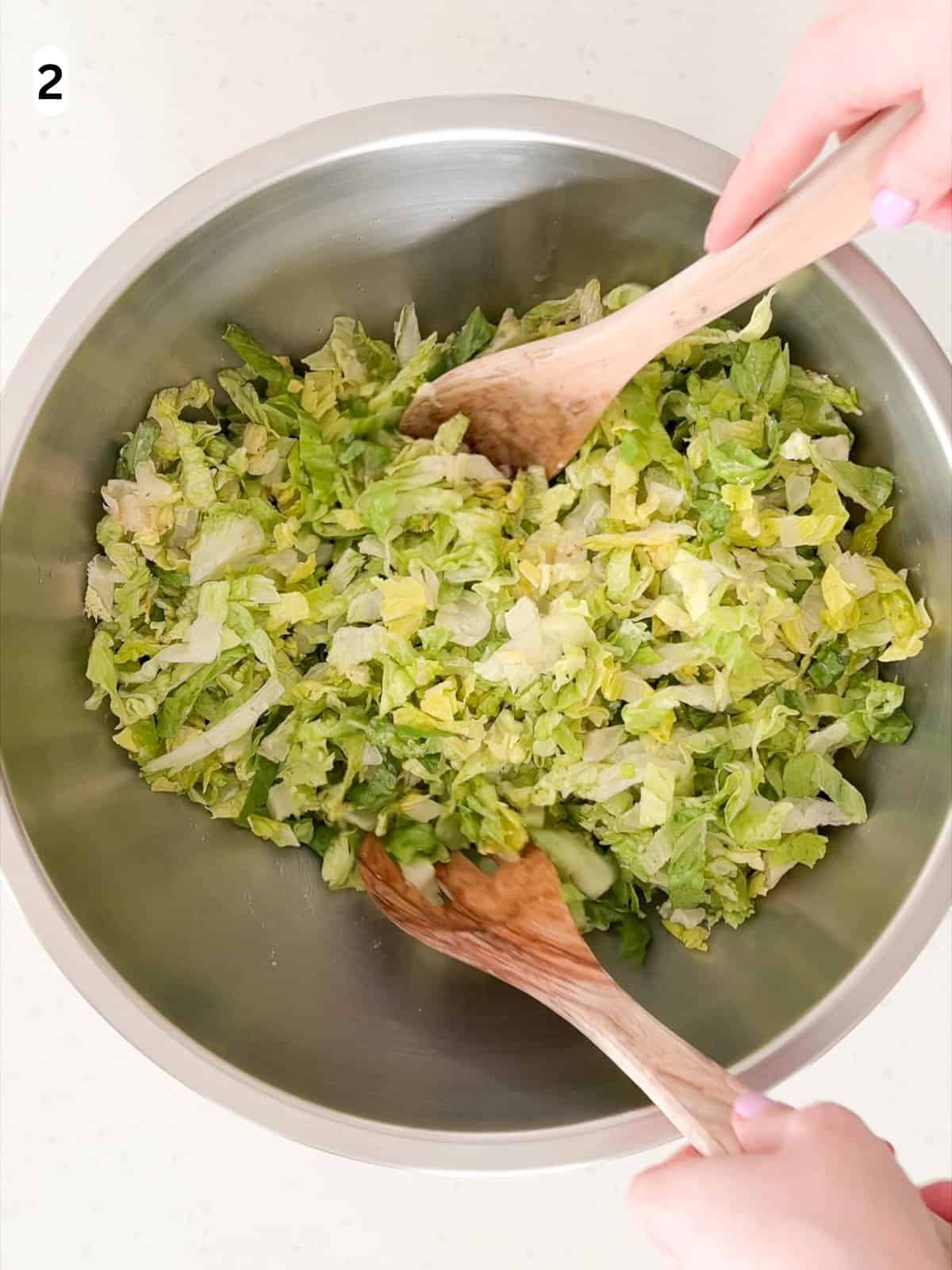 The lettuce is tossed in half of the vinaigrette.