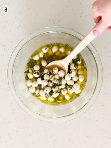 Mozzarella balls are tossed in the marinade until combined.