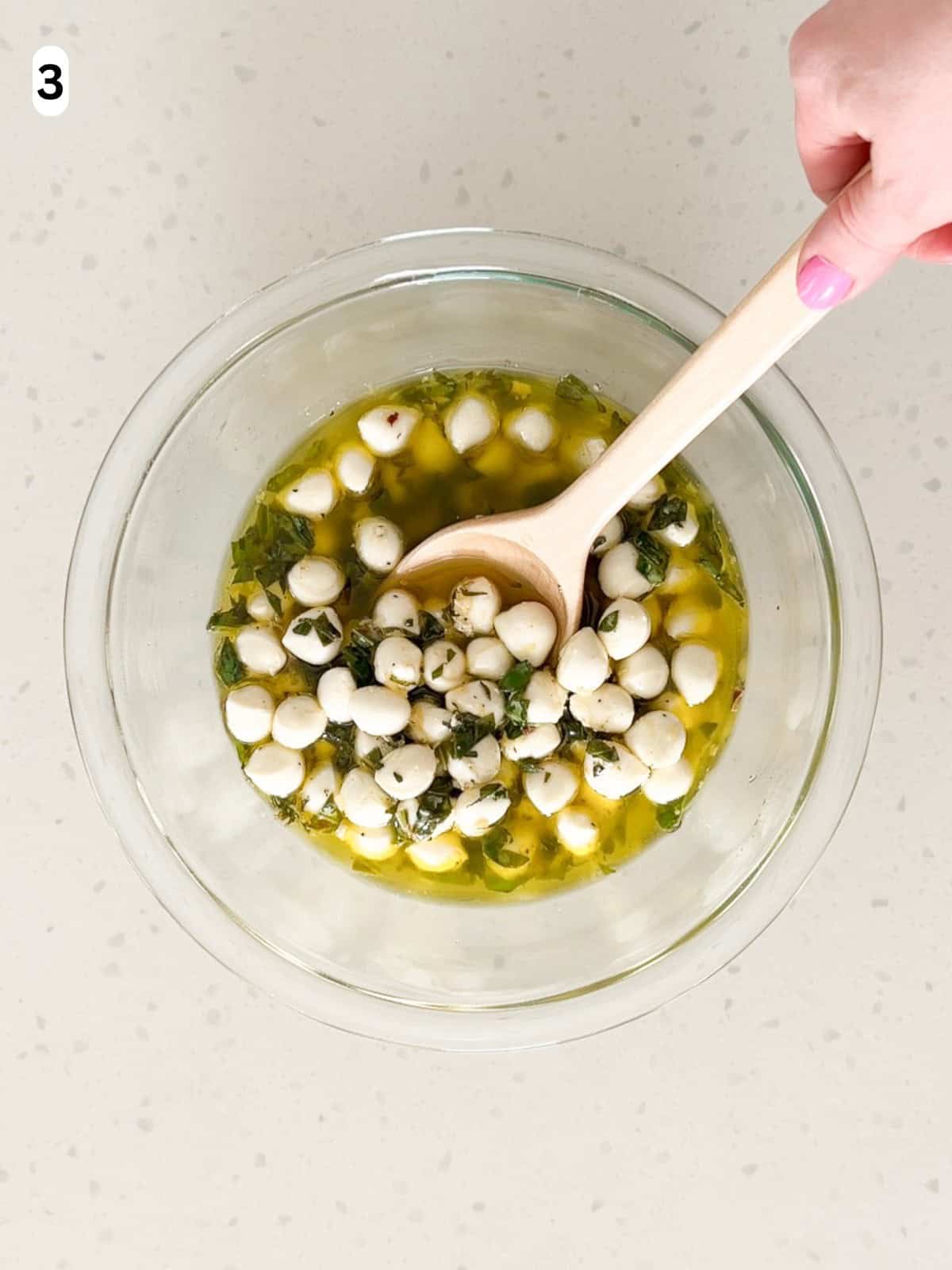 Mozzarella balls are tossed in the marinade until combined.