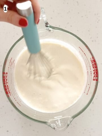 The ingredients for no egg vanilla ice cream are whisked together in a measuring cup.