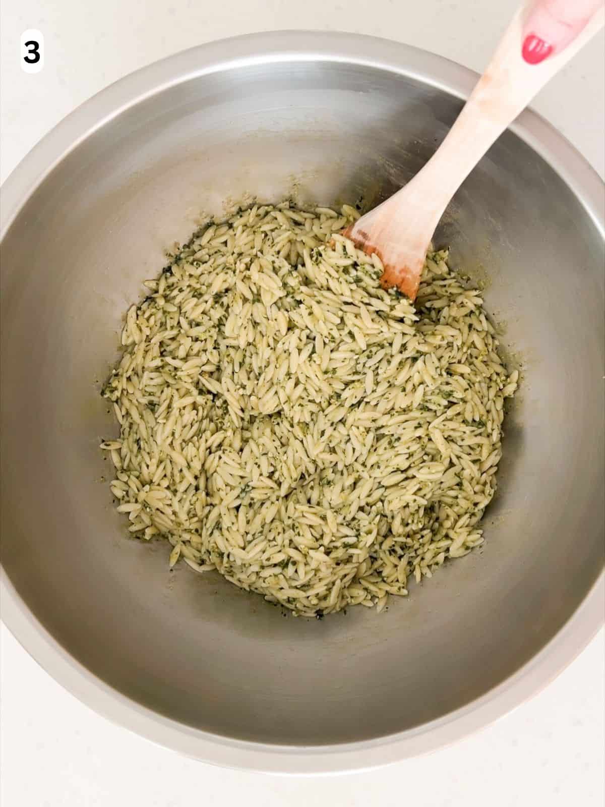 Orzo, pesto, lemon zest, and Parmigiano Reggiano are tossed until combined.